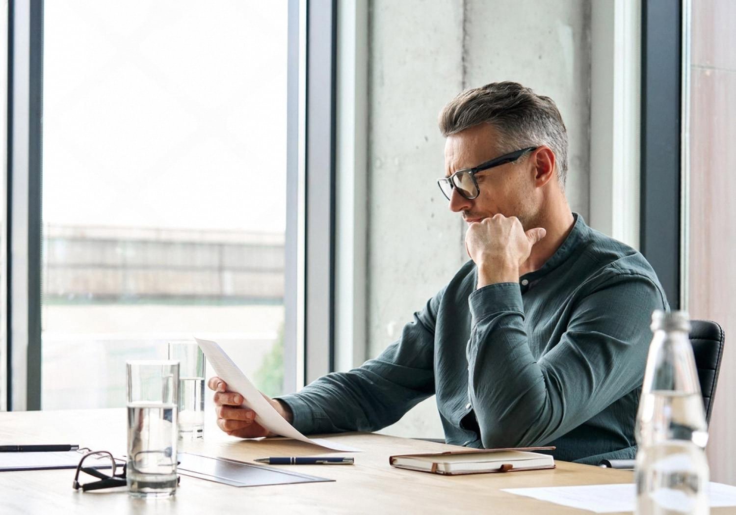 Business owner reading a due diligence findings document in a boardroom