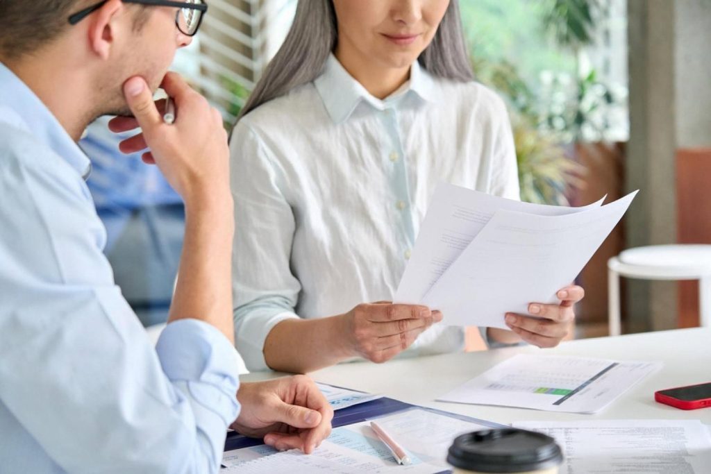 Two professionals reviewing a due diligence report at a desk with financial documents